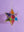 The Multi Coloured Iron & Glass Hanging Star Lantern by Ian Snow Ltd features intricate patterns and vibrant panels, suspended from a chain against a light purple background.
