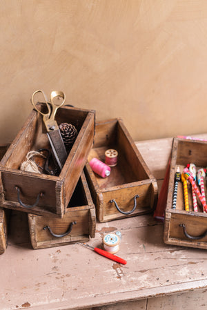 A Wooden Vintage Single Brick Mould by Ian Snow Ltd, filled with craft supplies like scissors, thread spools, pencils, and twine, creates a rustic workspace scene and offers a unique storage alternative.